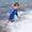 A young boy in a blue star-patterned rash vest and UV Protective Swim Shorts Multi Check, playing happily in the sea on a sunny day.