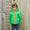 A boy in a Waterproof Puffer Jacket Green smiles, standing in front of a wooden door and fence.