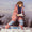 A young girl in a Blizzard Kids Ski Jacket Pink, holding snow outdoors. She's wearing sunglasses and a patterned ski suit.