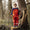 A young boy stands on a tree stump in Muddy Puddles waterproofs: bright orange dungarees, patterned long-sleeved top, and blue wellies.