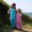 Two girls outdoors wearing Muddy Puddles Children's Waterproofs. One in blue rain cloud dungarees and one in pink star dungarees.