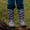 Muddy Puddles Children's Waterproofs: close-up of a child in purple lightning bolt wellies on a log, wearing blue jeans.
