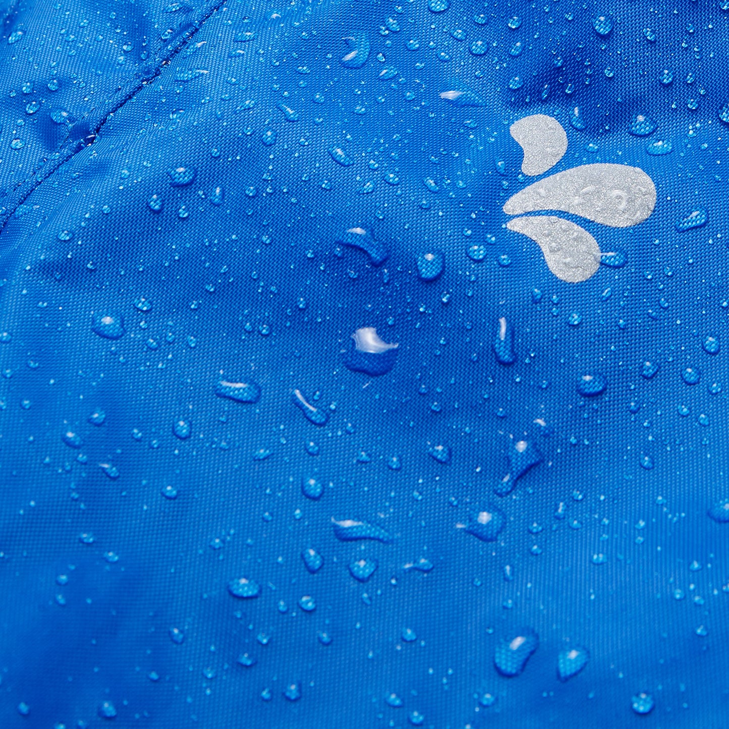 Close-up of Originals Waterproof Trousers Blue fabric, covered in water droplets, showing waterproof nature of the material and logo.
