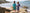 UV protective recycled swimwear. Two kids in swimwear holding hands on a beach. One suit has ice cream print, the other checks.