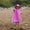 A happy child on a beach, wearing a UV Protective Sun Hat Pink Starfish, pointing towards the camera with a big smile.