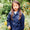 A young girl stands in a garden, wearing a navy Originals Waterproof Jacket, surrounded by flowers.