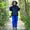A young child in Originals Waterproof Trousers Blue, stands in a garden in the rain, holding their hands up.