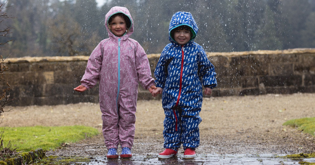 two children wearing Muddy Puddles waterproof puddle suits and smiling in the rain