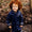 A young child smiling and wearing a Rainy Day Waterproof Jacket Navy in a woodland setting.