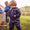 A child wearing the 'Originals Waterproof Puddle Suit Navy' playing with a stick in a bucket outdoors on a grassy field.