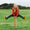 Muddy Puddlers!: A girl in a red coat & green wellies, doing the splits on a post in a green field. She's smiling at the camera.