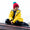 A boy in a Puddleflex Waterproof Fleece Lined Jacket in yellow, sitting on a boat wearing a red hat with a blue pom pom.