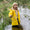 A blonde girl in a stream, wearing a Puddleflex Waterproof Fleece Lined Jacket in yellow. She's smiling and appears to be enjoying herself.