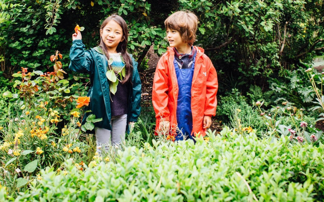 boy and girl stood in garden wearing vibrant muddy puddles waterproofs