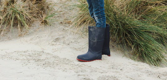 boy wearing navy wellies standing on grassy sand dunes