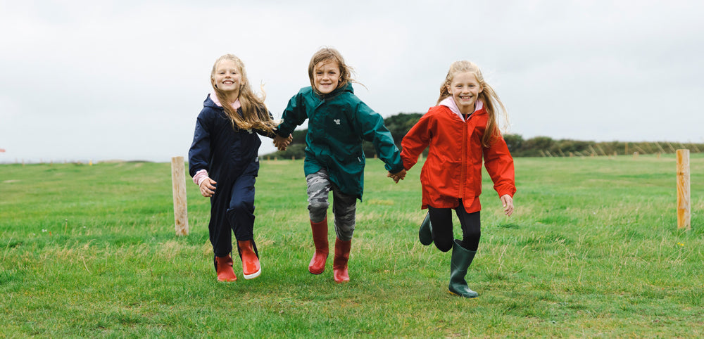 children running across field wearing muddy puddles navy, green and red originals waterproof jackets