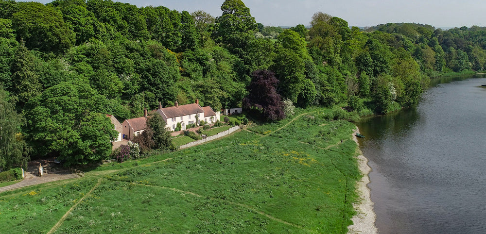 Scenic countryside cottage beside a lush forest and riverside, ideal for outdoor family adventures