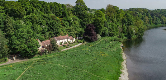 Scenic countryside cottage beside a lush forest and riverside, ideal for outdoor family adventures