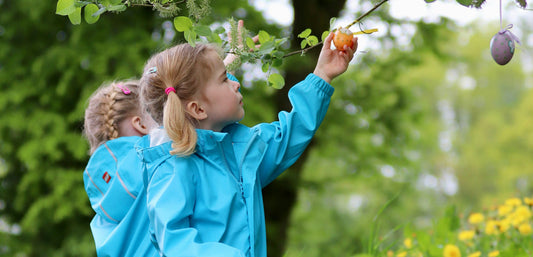 children looking at coloured eggs hanging from a tree