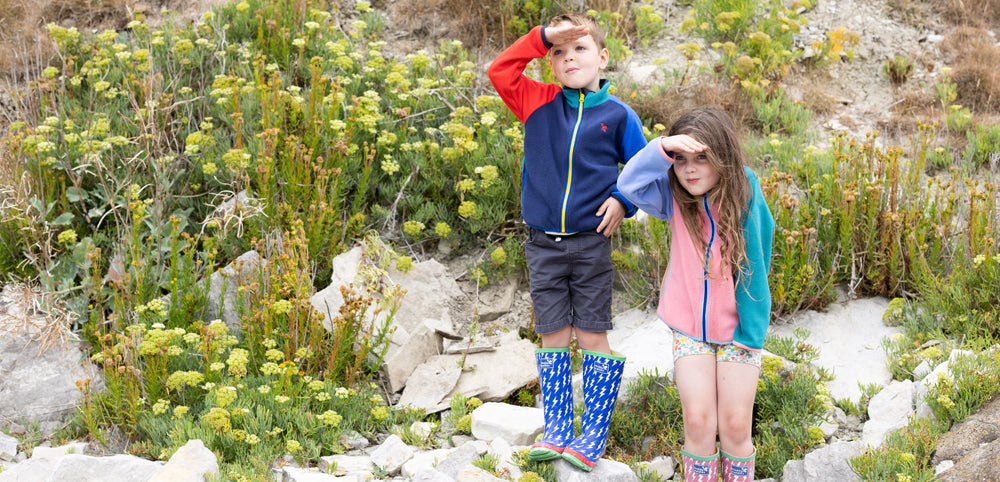 boy and girl looking out to sea wearing muddy puddles fleece jackets