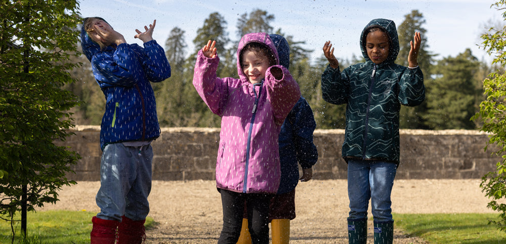 group of children wearing vibrant muddy puddles raincoats feeling raindrops with their hands