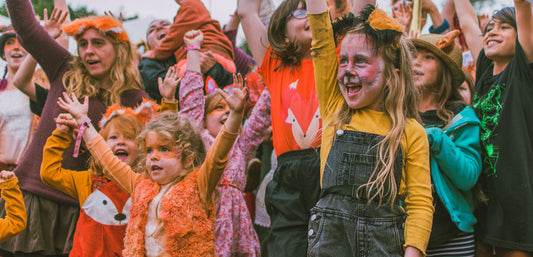 Group of children in animal costumes outdoors, wearing colorful rainwear and face paint, celebrating