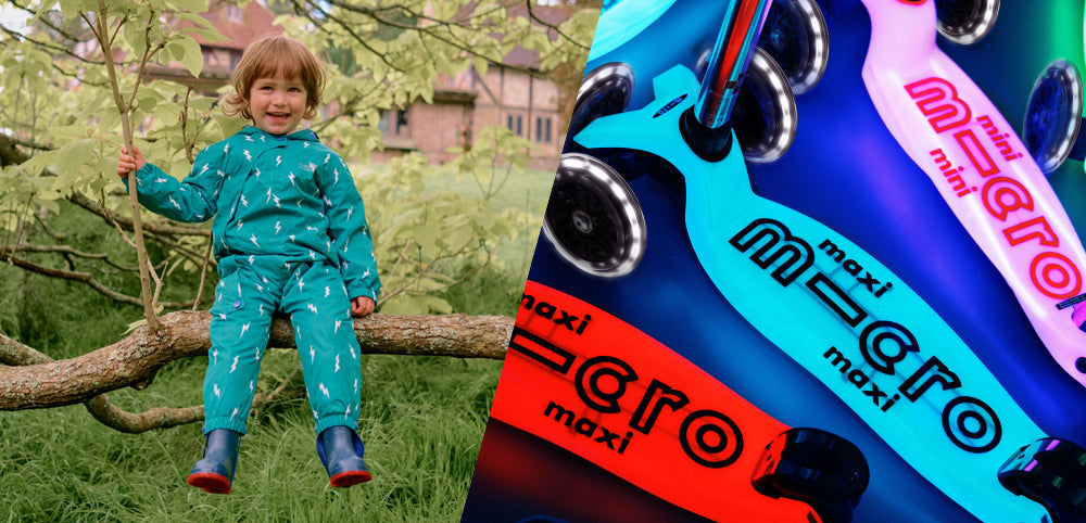 Child in teal waterproof rainwear sitting on a tree, colorful kids scooters beside them