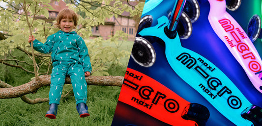 Child in teal waterproof rainwear sitting on a tree, colorful kids scooters beside them