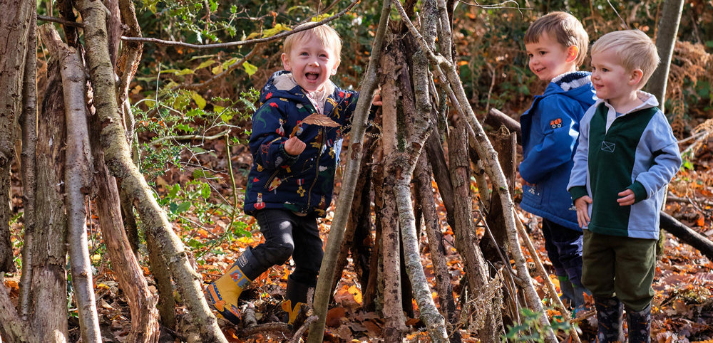 toddler boys making a woodland den