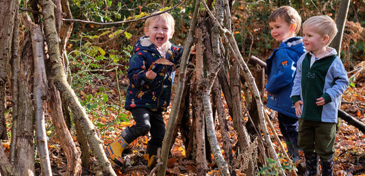 toddler boys making a woodland den
