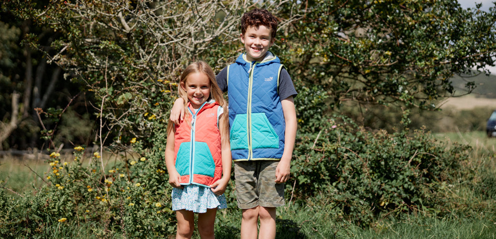 boy and girl stood in front of tree wearing colourful muddy puddles gilets