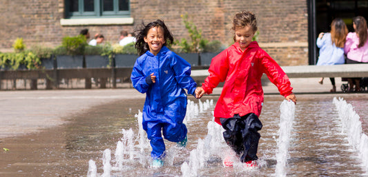 girls running through fountains, wearing vibrant muddy puddles waterproofs