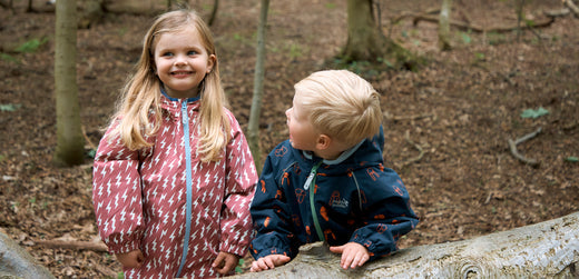 Children in waterproof jackets playing outdoors in a woodland setting