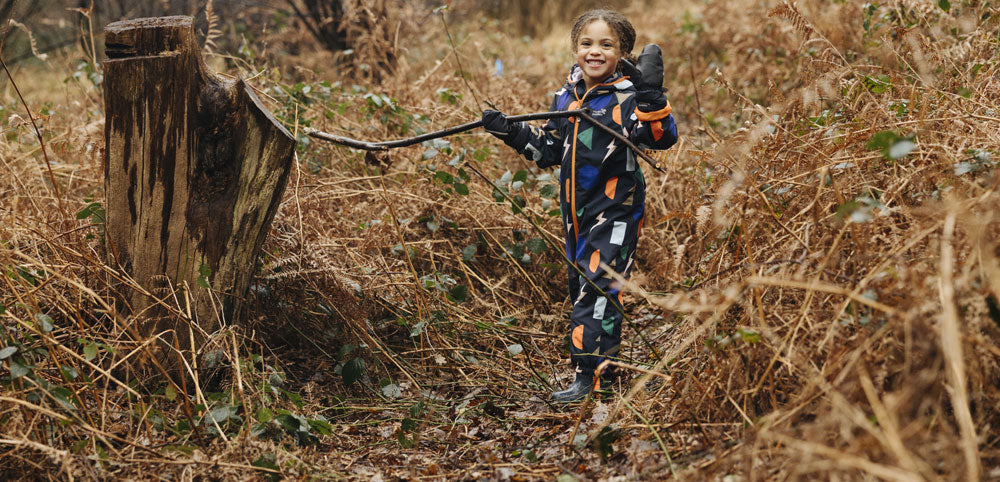 Child wearing waterproof rain suit playing outdoors in a woodland area