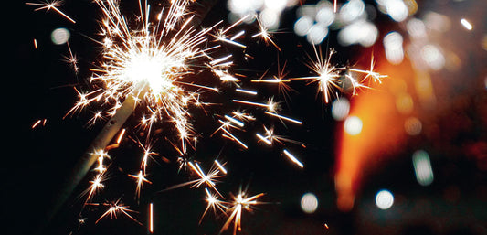 Close-up of a bright sparkler glowing against a dark background with festive sparks