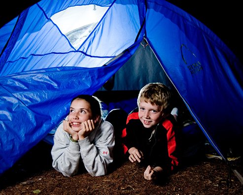boy and girl lying in a blue tent in the dark