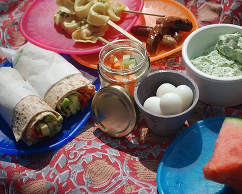 selection of healthy picnic food on a colourful picnic blanket