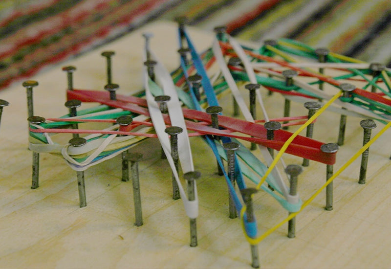 coloured rubber bands looped across nails on a wooden base