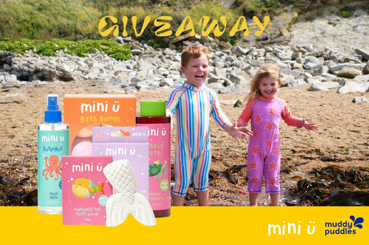 Children in colorful waterproof suits playing on a beach with Mini U bath and hair products giveaway.