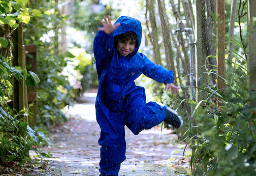 boy running through rain, wearing vibrant blue muddy puddles puddlesuit