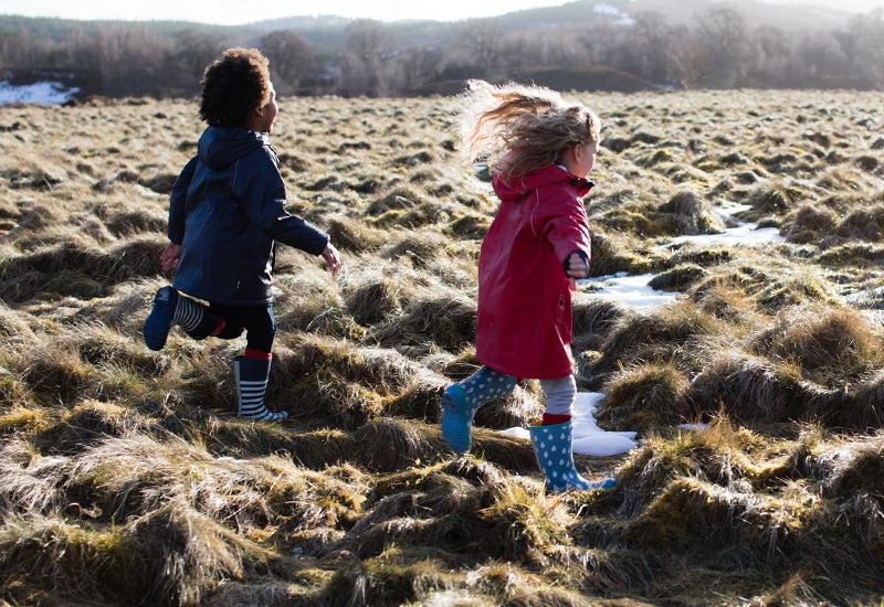 children running across wet heathland, wearing muddy puddles raincoats and wellies