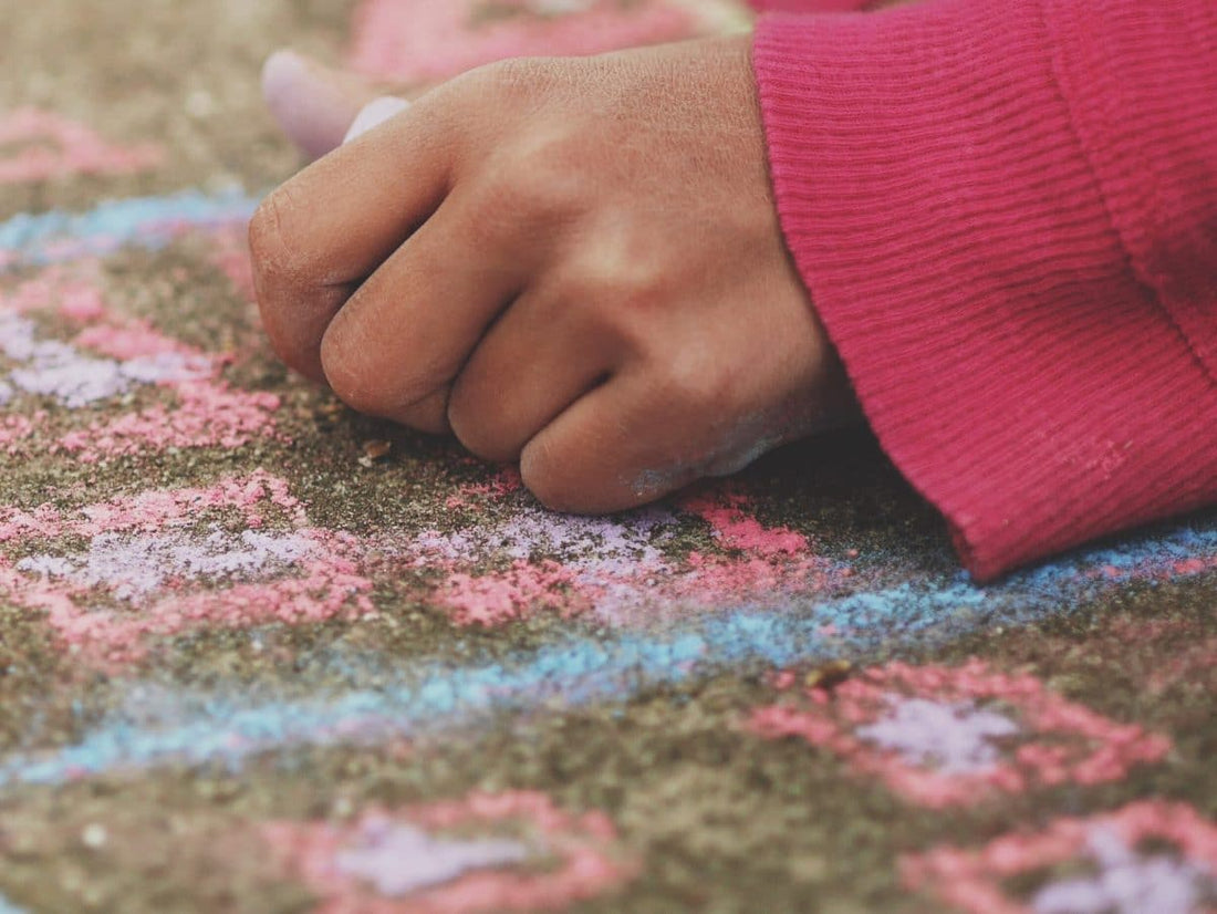 child drawing on the ground with coloured chalk