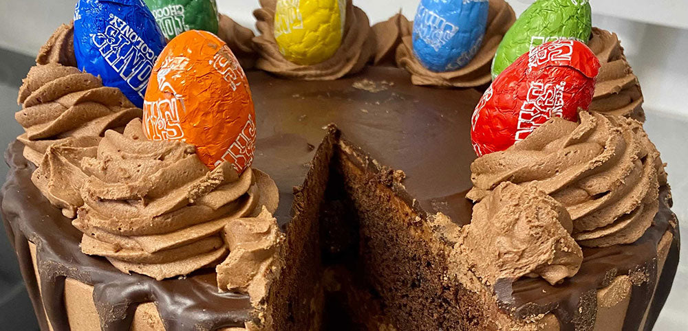Chocolate cake topped with colorful chocolate eggs and chocolate frosting swirls