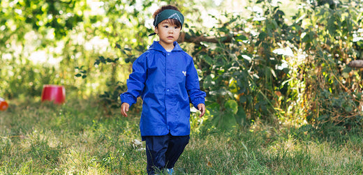 boy wearing blue waterproof jacket and navy waterproof trousers