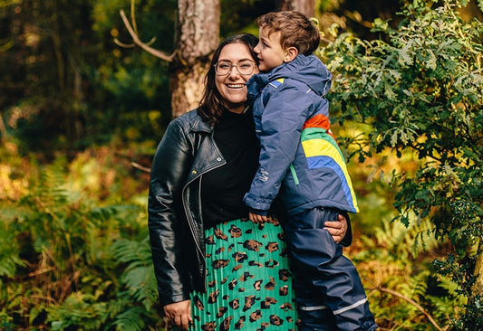 mother and child posing in woodland area, boy is wearing muddy puddles waterproofs