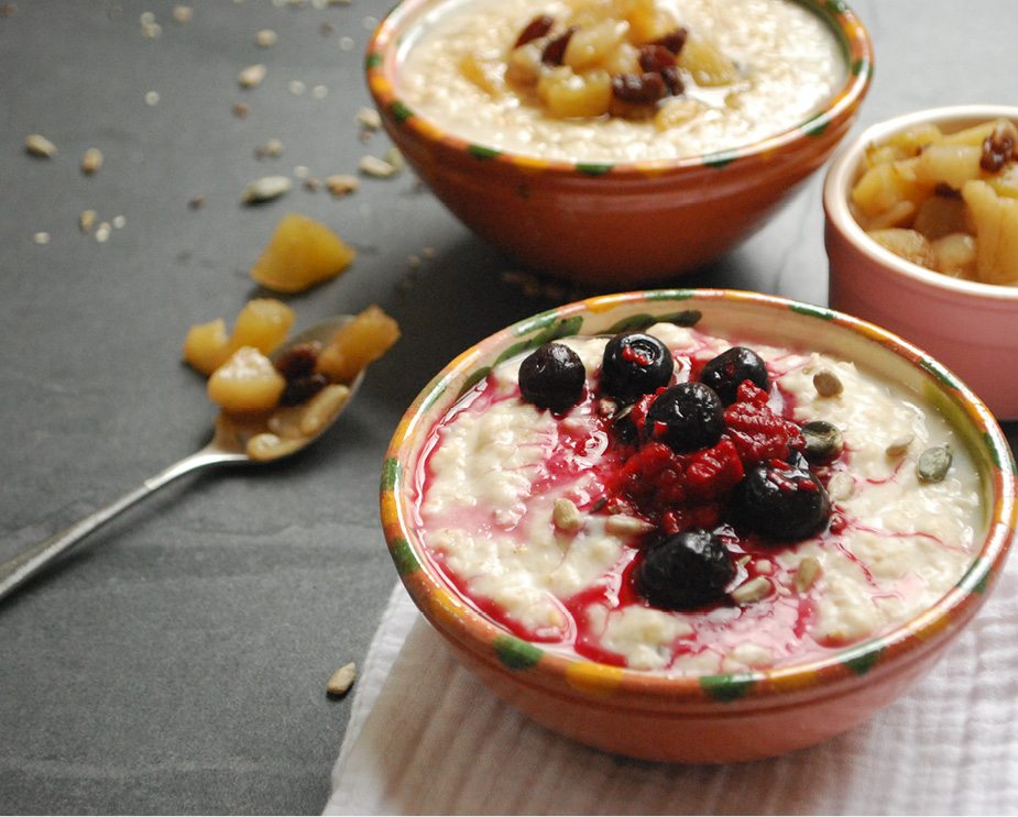 close up of bowls of porridge with blueberry and apple toppings