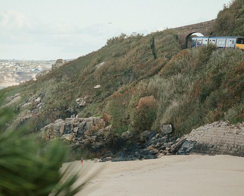 picturesque photo of a sandy beach with a grassy hillside
