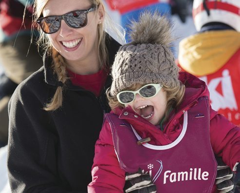 close up of mother and daughter smiling and laughing while wearing skiing gear