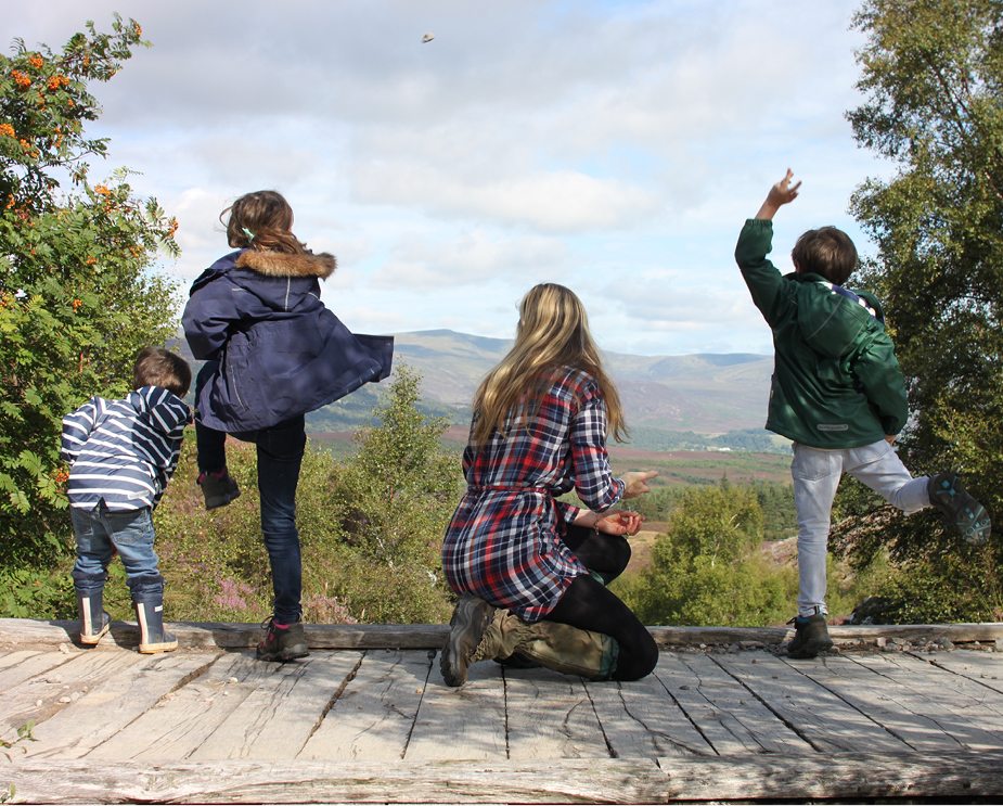 children and mother on a wooden boardwalk looking into the distance