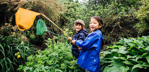children holding long fishing nets wearing muddy puddles blue and nay waterproof jackets